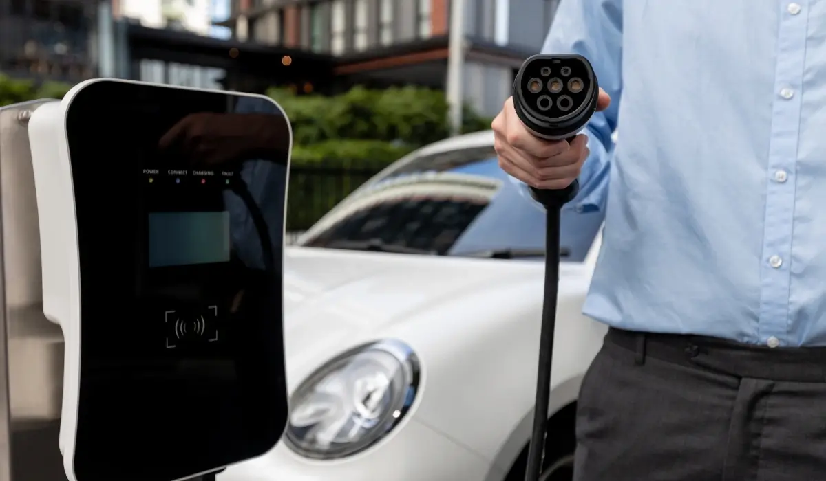 Property resident holding an EV charging connector beside a wall-mounted charging station