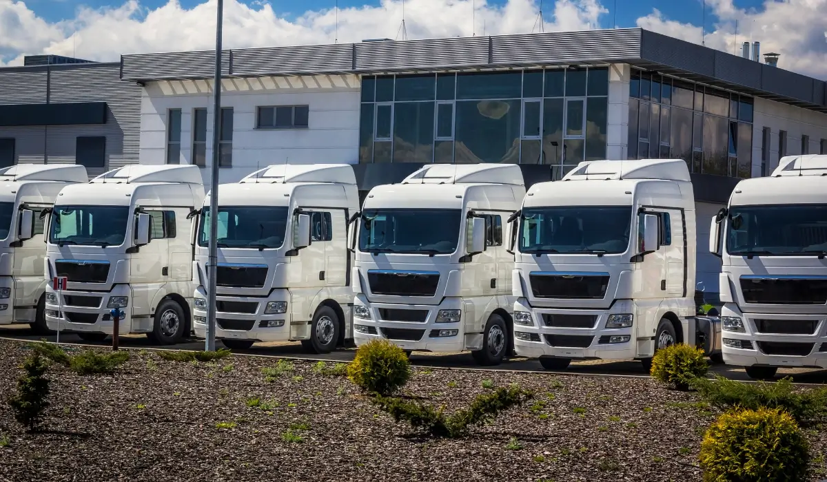 Row of white commercial trucks parked outside a fleet facility.