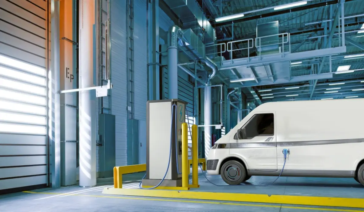 Electric delivery van connected to a charging station inside a fleet depot