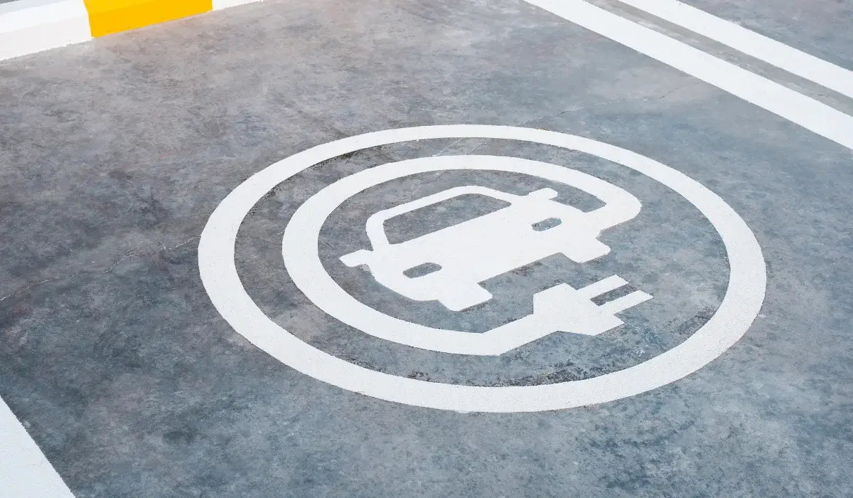 Electric vehicle charging station parking space marked with a white EV charging symbol.