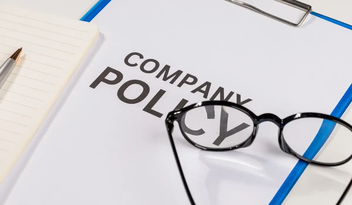 Company policy document with eyeglasses and a pen on a desk.