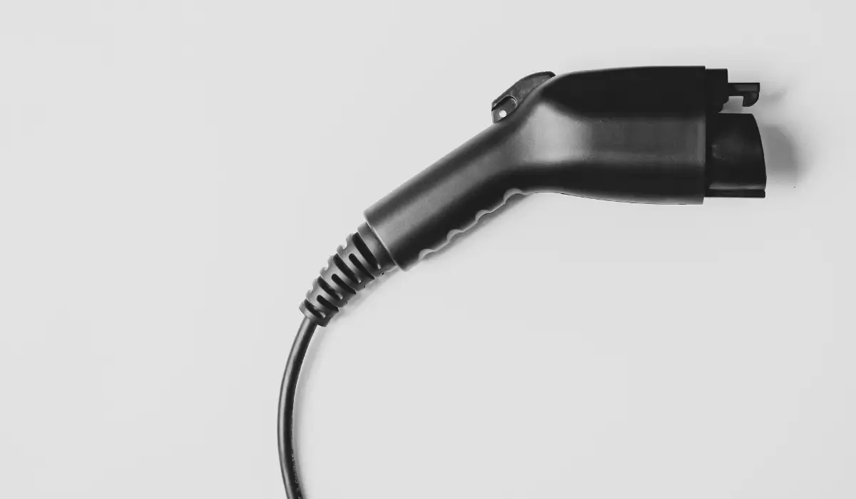An electric vehicle (EV) charging connector with its cable attached is laid horizontally against a plain white background.