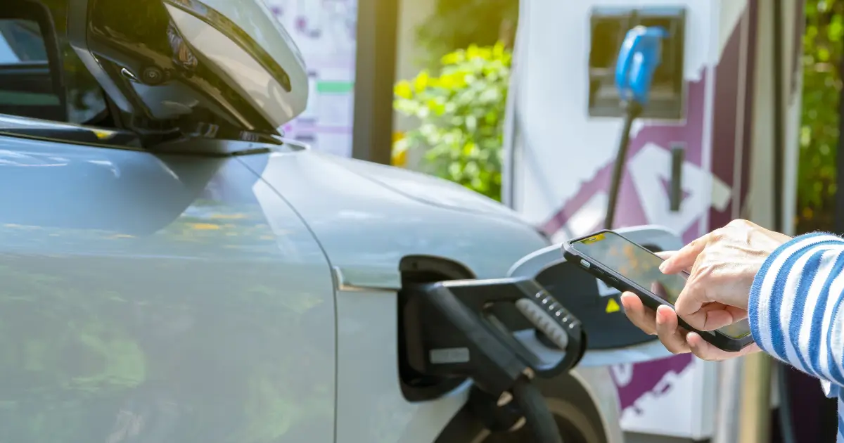 Driver using a smartphone app to start an EV charging session at a public charging station