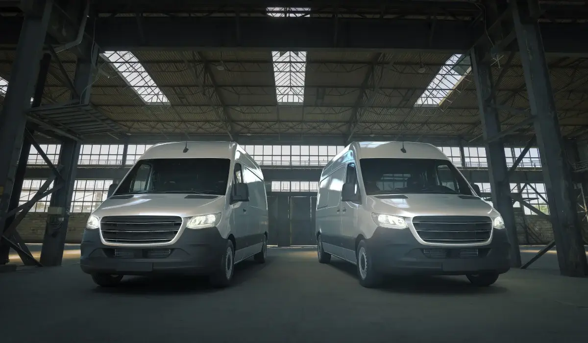 Two white commercial delivery vans parked inside a large industrial depot warehouse.