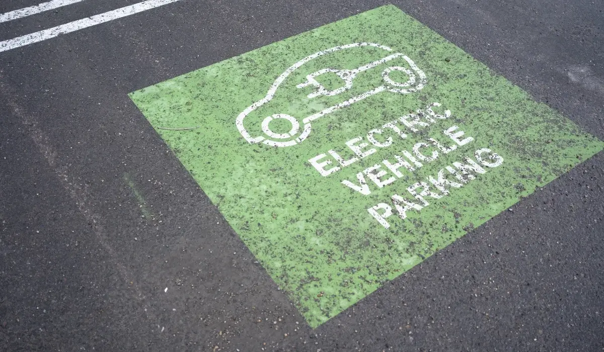 Green electric vehicle parking space marked with a white EV charging symbol on asphalt.