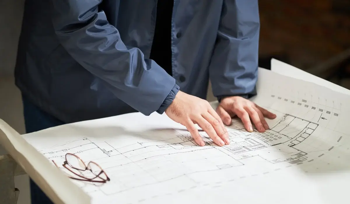 Professional reviewing a building floor plan on a table during depot layout planning.